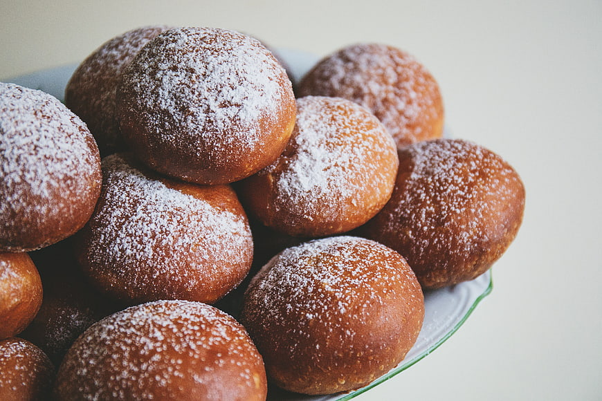 Close-up of golden donuts dusted with powdered sugar on a plate