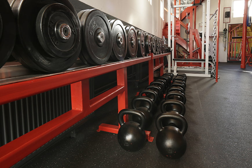 Rows of kettlebells and weight plates in a gym