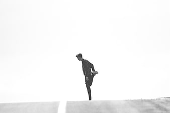 Silhouette of man stretching leg on road in black and white