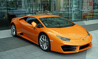 Orange Lamborghini Huracan parked outside modern glass building