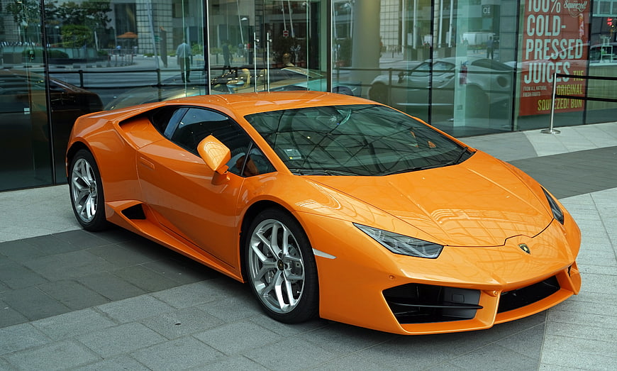Orange Lamborghini Huracan parked outside modern glass building