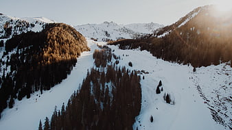 Aerial view of snowy mountain ski slopes at sunset