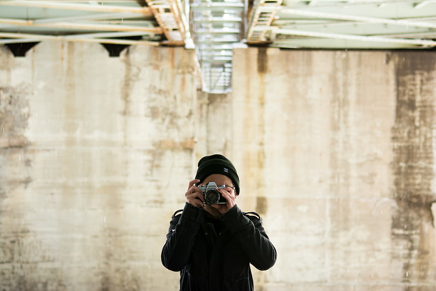 Photographer with vintage camera under concrete bridge