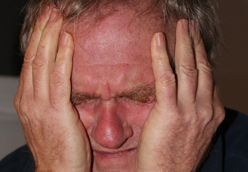 Senior man holding head in pain and despair