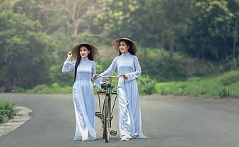 Two Vietnamese Women in Ao Dai and Conical Hats with Bicycle