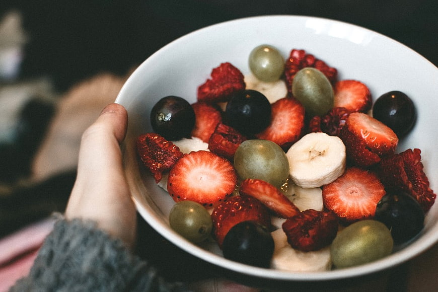 Hand Holding Bowl of Fresh Mixed Fruit and Yogurt
