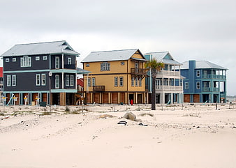 Row of colorful beach houses under construction on sandy shore