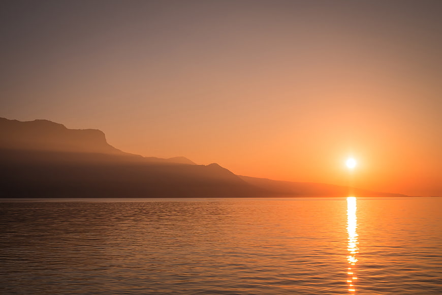 Serene Sunset Over Calm Lake with Mountain Silhouette