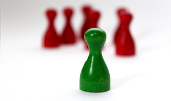 Green game piece facing group of red pieces on white background