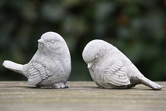 Two Stone Bird Figurines on Wooden Surface