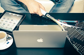 Tennis racket, laptop, tablet, and coffee on a table