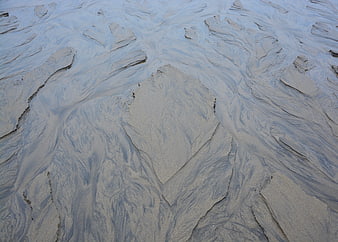 Abstract wet sand texture with water channels on a beach at low tide