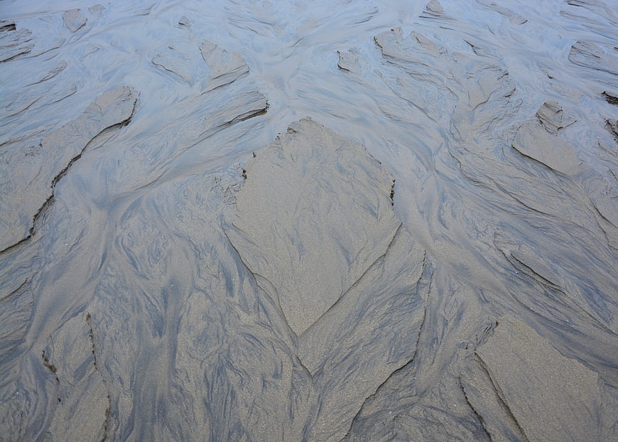 Abstract wet sand texture with water channels on a beach at low tide