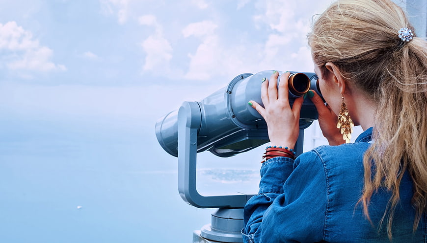 Woman Looking Through Coin-Operated Binoculars at Ocean View