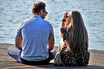 Couple Sitting on Wooden Pier by Water