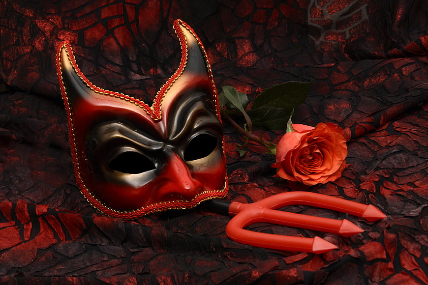 Red devil mask with trident and rose on dark background