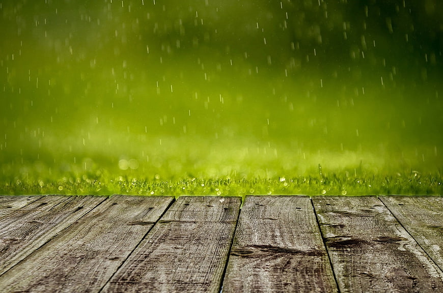 Wooden Table Surface with Rainy Green Grass Background