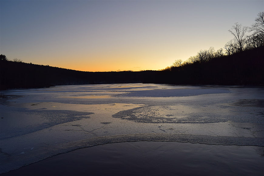 Frozen Lake Landscape at Sunset with Silhouetted Trees