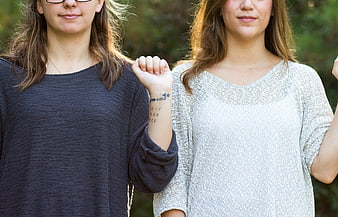 Two women raising fists with solidarity tattoo on wrist