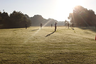 Soccer players training on grassy field at sunrise