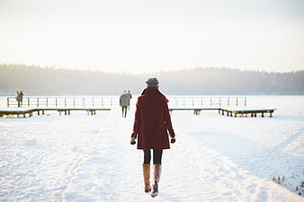 Woman in Red Coat Walking on Snowy Path