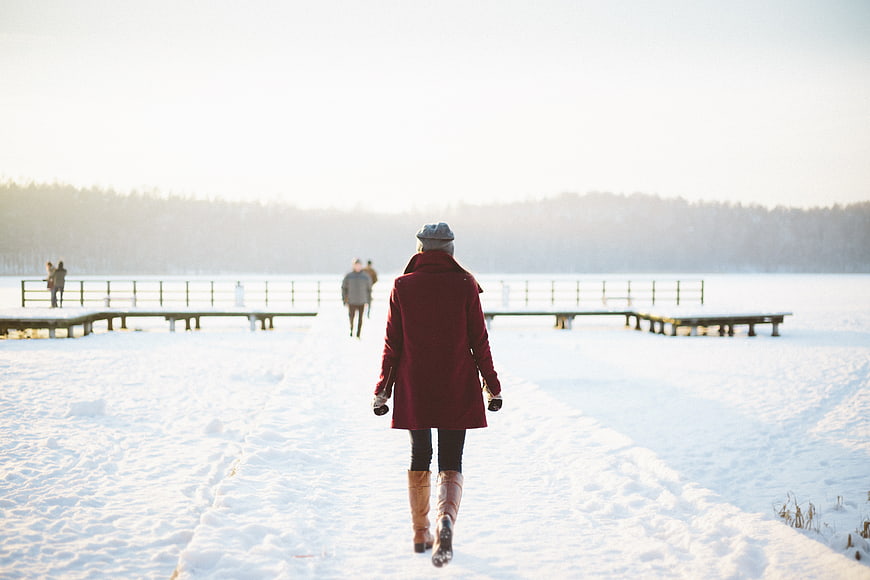 Woman in Red Coat Walking on Snowy Path