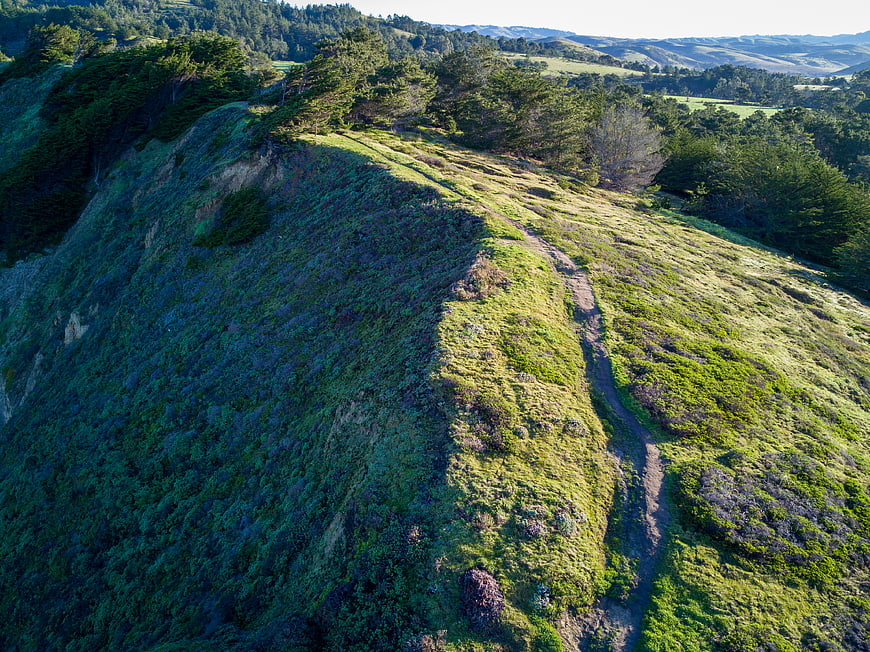 Aerial view of a hiking trail on a green mountain ridge
