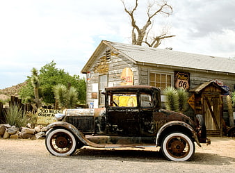 Rusty vintage car parked in front of weathered Route 66 general store