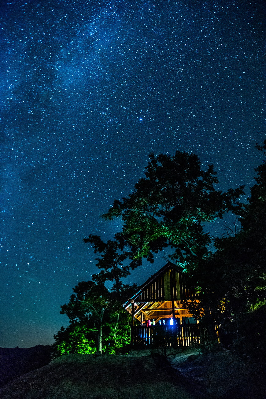 Illuminated wooden cabin under starry night sky