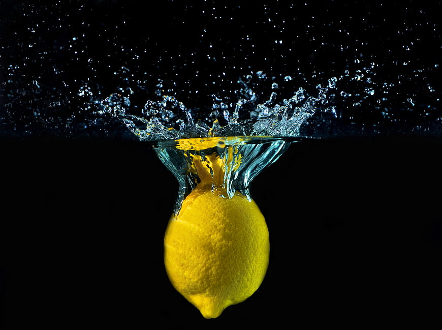 Fresh Lemon Splashing into Water on Black Background