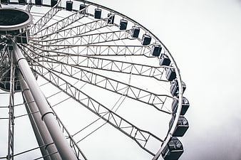 Low angle view of a large ferris wheel against a white sky