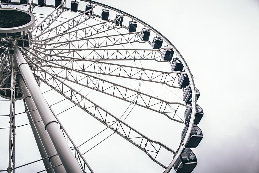 Low angle view of a large ferris wheel against a white sky
