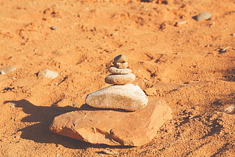 Stacked stones on red sand in desert landscape