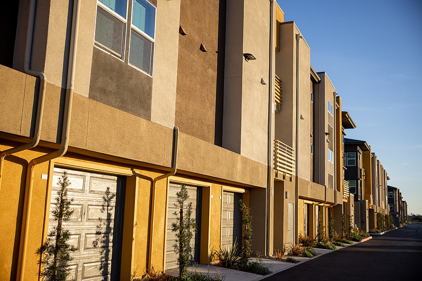 Modern beige townhouses with garage doors and blue sky