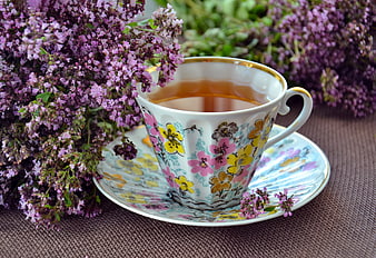 Herbal tea in floral cup with fresh oregano flowers