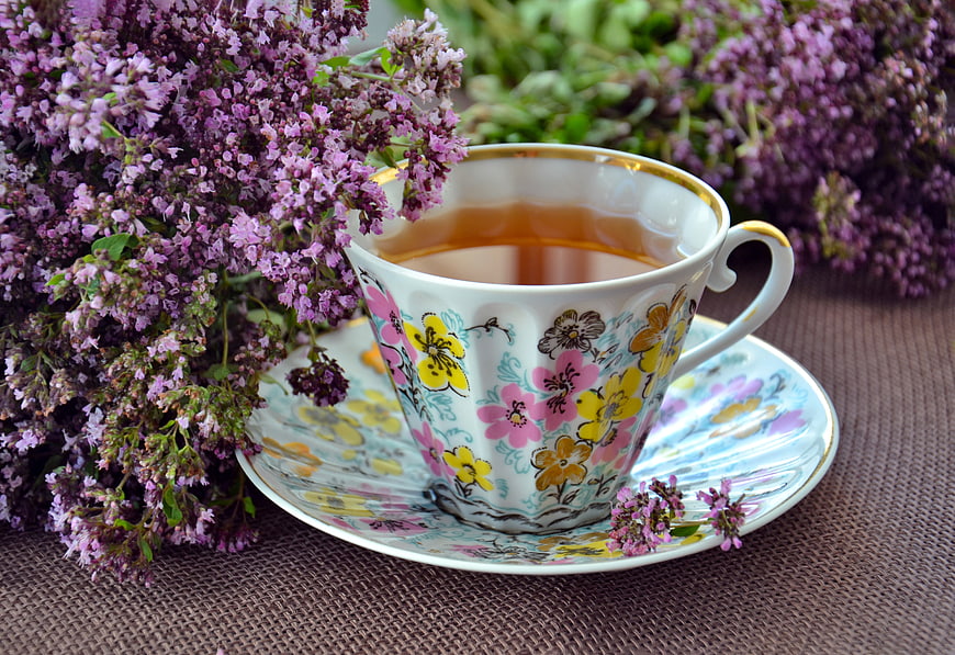 Herbal tea in floral cup with fresh oregano flowers