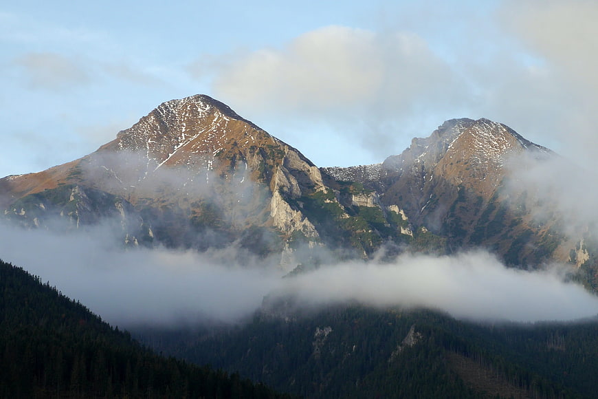 Misty mountain peaks with snow and autumn foliage
