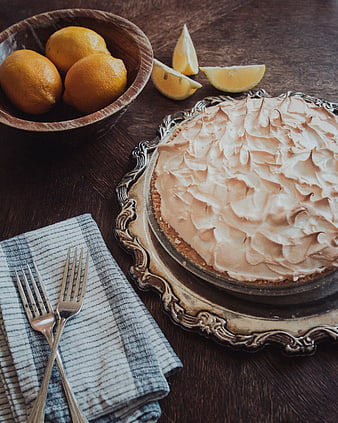 Homemade Lemon Meringue Pie with Fresh Lemons on Wooden Table