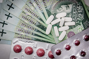 White pills and blister packs on Polish Zloty banknotes