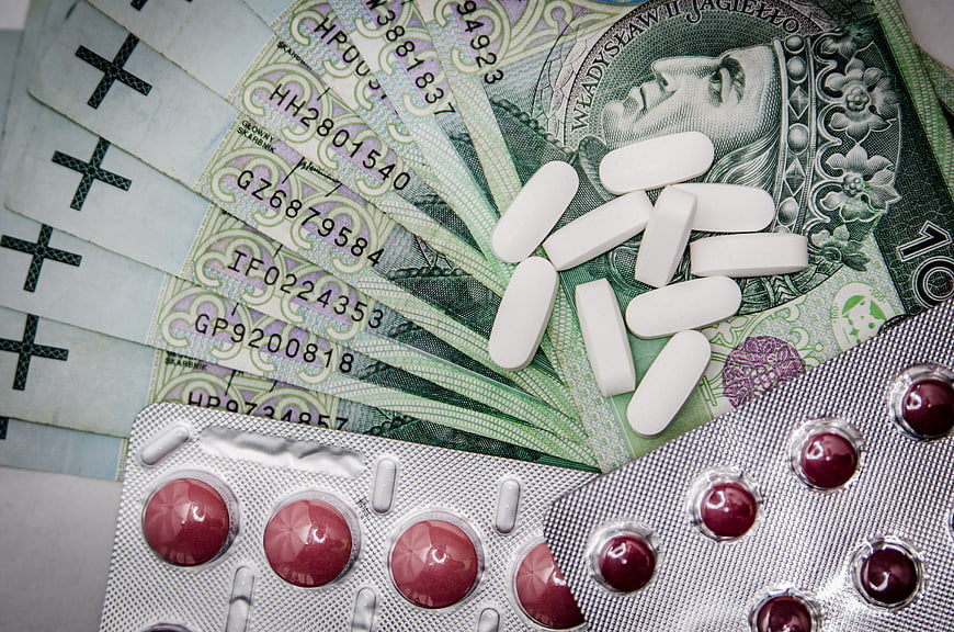 White pills and blister packs on Polish Zloty banknotes