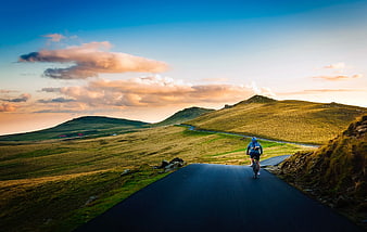Cyclist Riding on Winding Mountain Road at Sunset