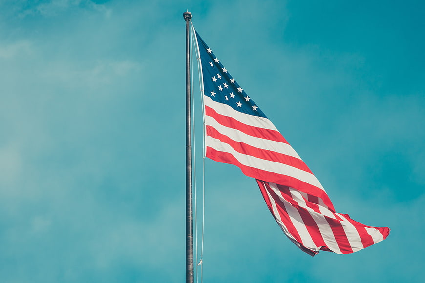American Flag Waving Against Blue Sky Background