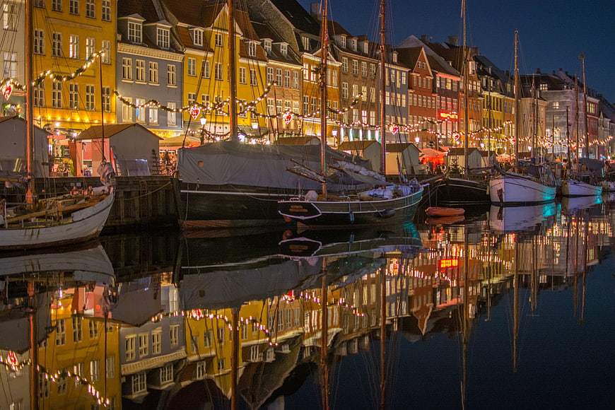 Colorful Nyhavn harbor at night with boats and reflections