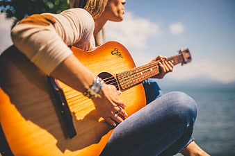 Woman Playing Acoustic Guitar by the Sea