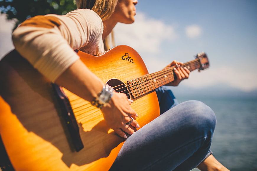 Woman Playing Acoustic Guitar by the Sea