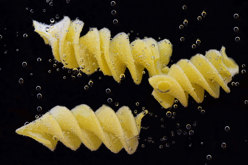 Spiral Pasta Floating in Water with Bubbles