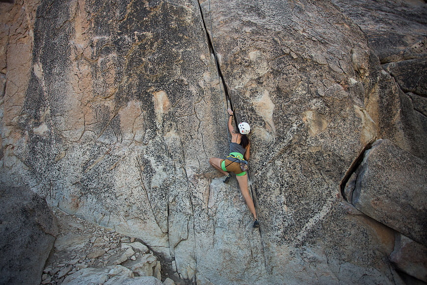 Woman rappelling down a massive granite rock face