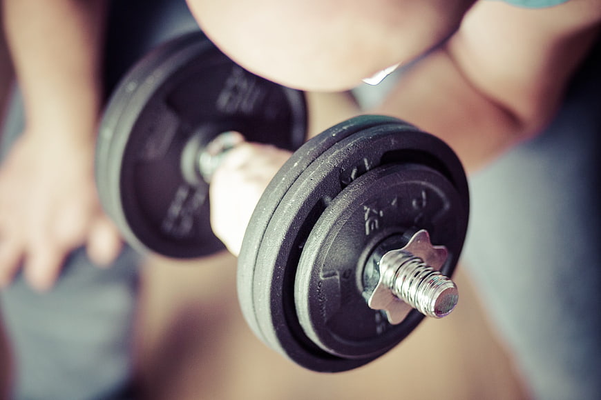 Close-up of hands lifting black dumbbells for strength training