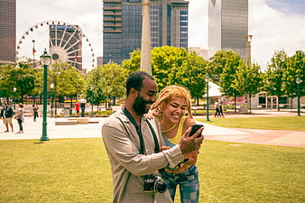 Happy Diverse Couple Looking at Smartphone in City Park