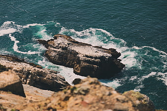 Aerial View of Turquoise Waves Crashing Against Rocky Coastline
